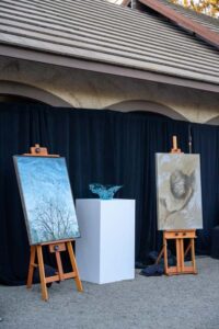 Three artworks on easels and pedestals