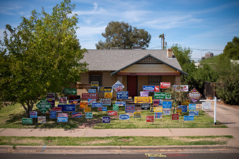 A suburban house with more than fifty lawn signs for past presidential candidates in the yard.