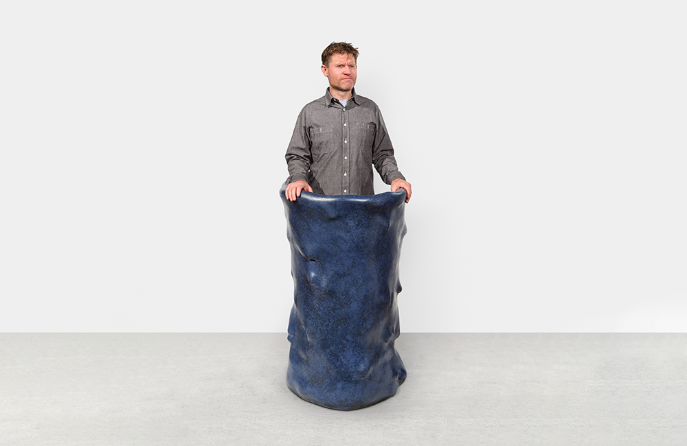 A person standing behind a large blue podium with a lumpy surface