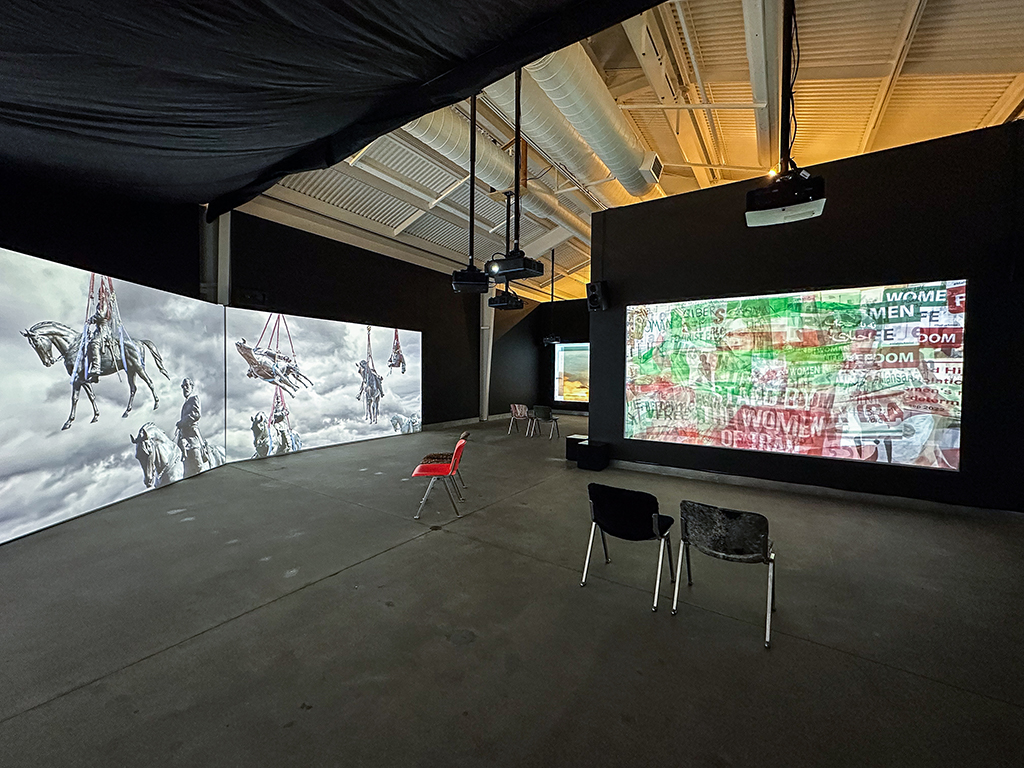 large gallery room with multiple projected video works