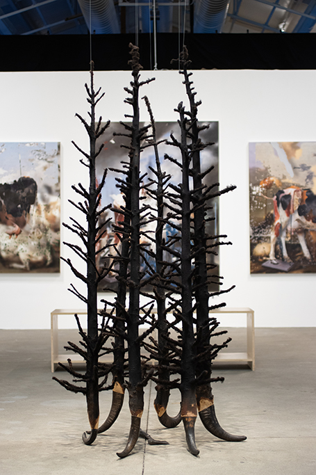 A sculpture of black bare trees in a large gallery