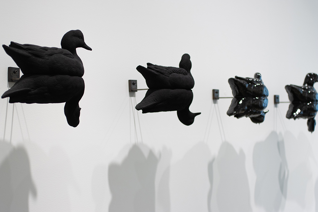 A sculpture of black duck decoys mounted on a wall