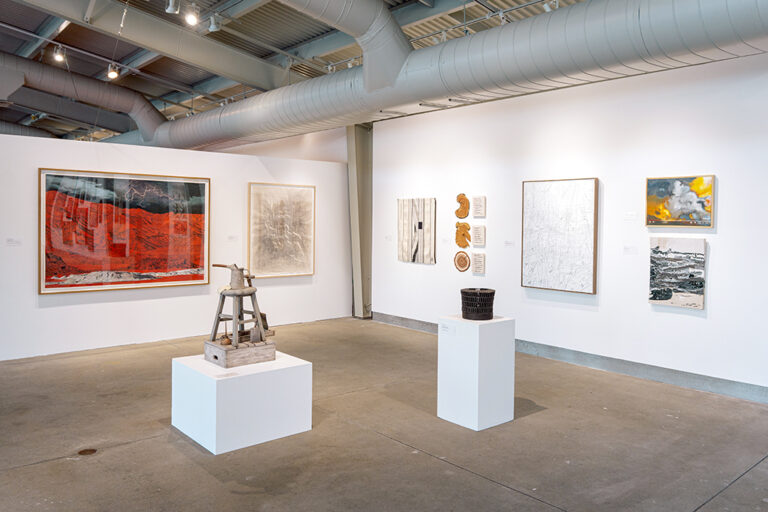 An assortment of artworks, including paintings, drawings, and sculpture, in a gallery.