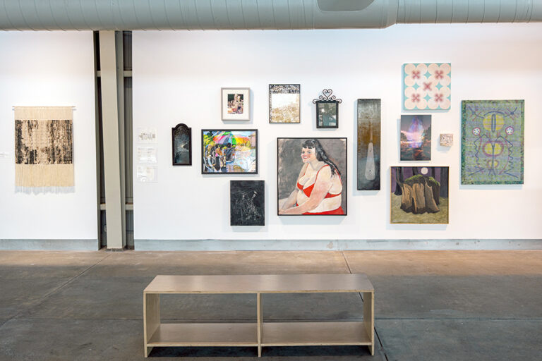 An assortment of artworks, including paintings, drawings, in a gallery.