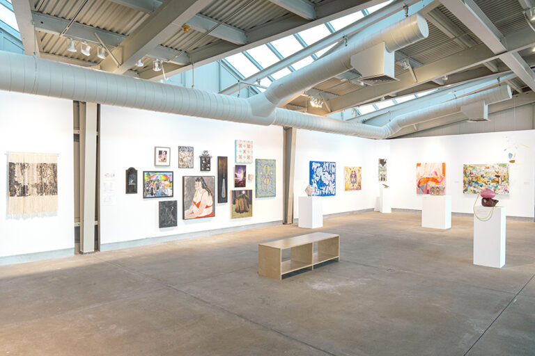 An assortment of artworks, including paintings, drawings, and sculpture, in a gallery.