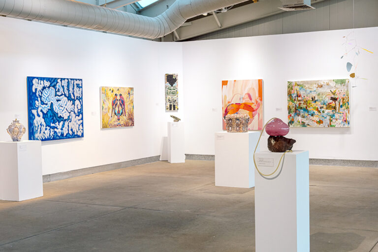 An assortment of artworks, including paintings, drawings, and sculpture, in a gallery.