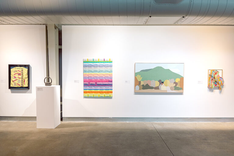 An assortment of artworks, including paintings, drawings, and sculpture, in a gallery.